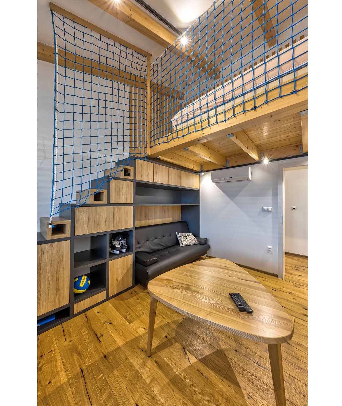 industriální interiér s dřevěným nábytkem a síti místo zábradlí