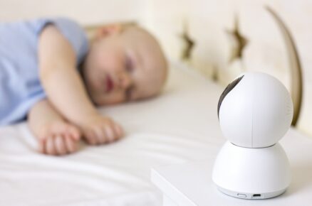 malý chlapeček spí na posteli doma s kamerou baby monitor.