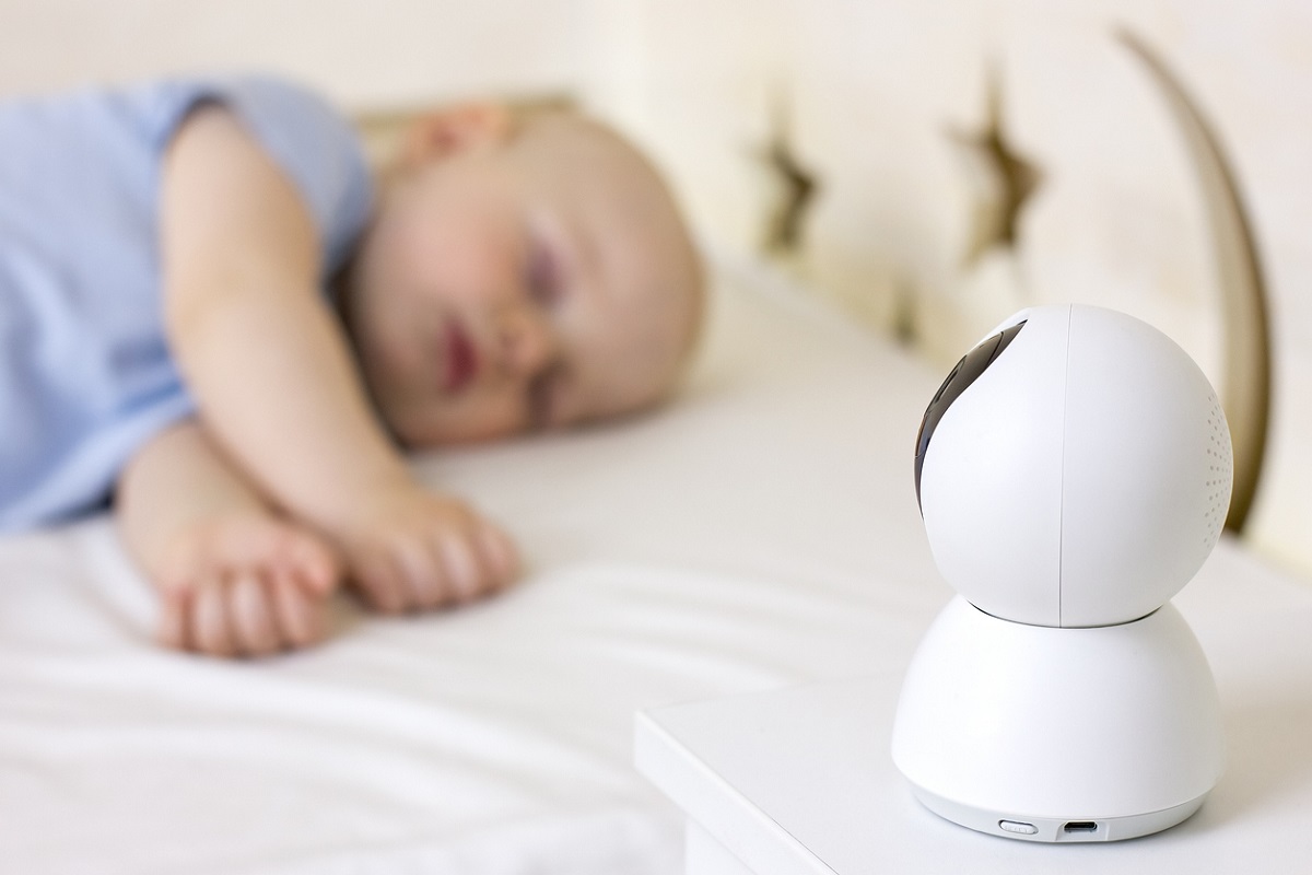 malý chlapeček spí na posteli doma s kamerou baby monitor.